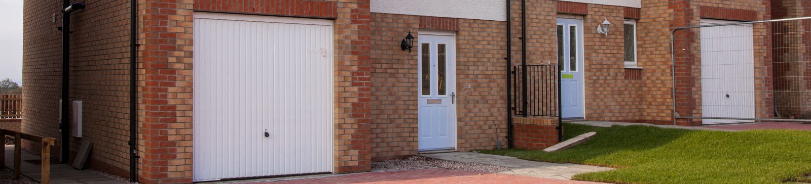 Row of brick houses with white up-and-over garage doors and entryways in Shakopee, MN