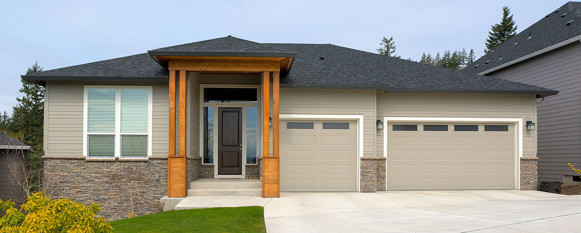 Contemporary house exterior with two beige garage doors and stone accents in Shakopee, Minnesota